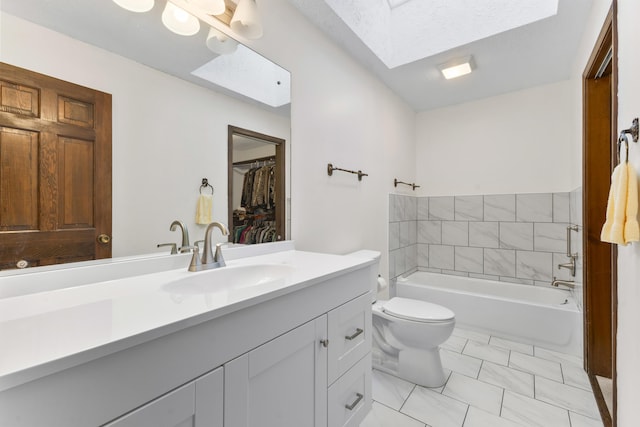 bathroom with vanity, a skylight, tile patterned flooring, toilet, and a tub to relax in