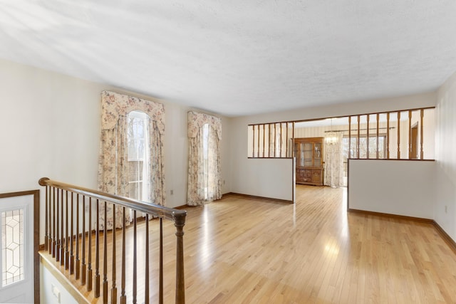 spare room with a textured ceiling and light wood-type flooring