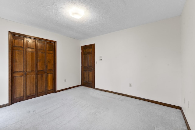 unfurnished bedroom with light colored carpet, a textured ceiling, and a closet