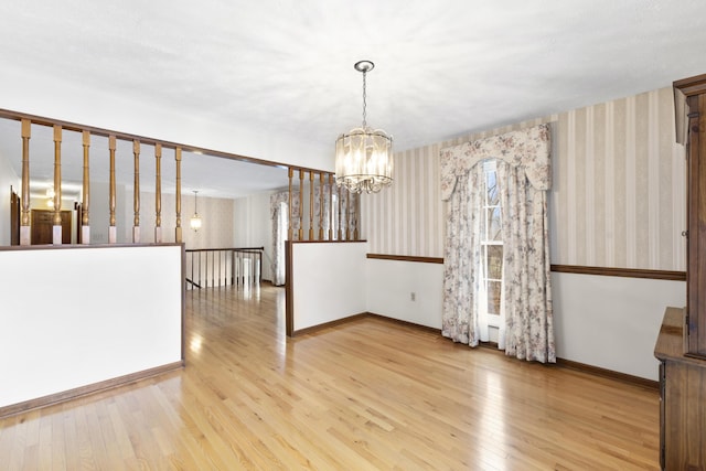 unfurnished dining area featuring a chandelier and light hardwood / wood-style flooring