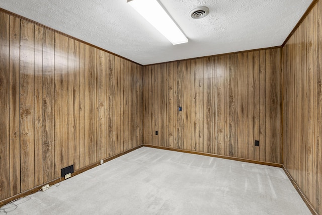 carpeted spare room featuring a textured ceiling and wood walls