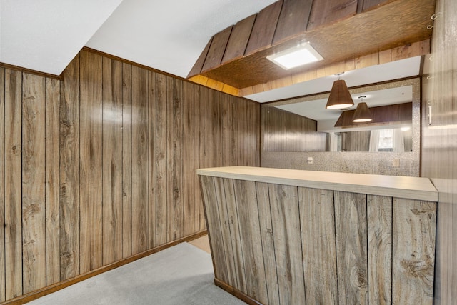 bar with wood walls, light colored carpet, and hanging light fixtures