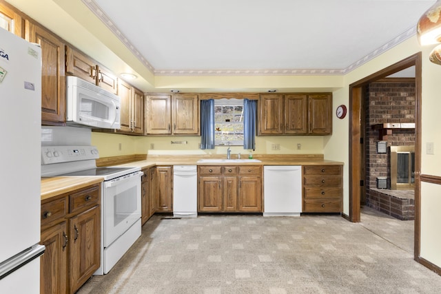 kitchen featuring sink, a brick fireplace, crown molding, light colored carpet, and white appliances