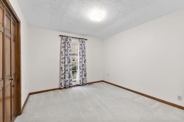 unfurnished room featuring light carpet and a textured ceiling