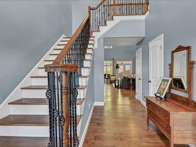 stairway featuring wood-type flooring and a high ceiling