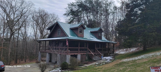 view of front of property with concrete driveway, a sunroom, stairway, metal roof, and an attached garage