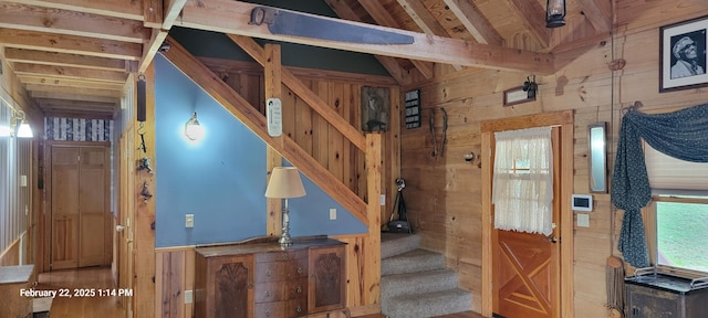 staircase featuring lofted ceiling with beams and wood walls