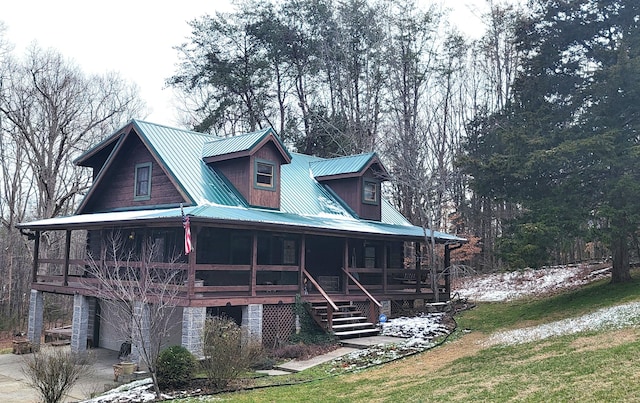 view of front of property with a front yard, a sunroom, metal roof, a garage, and stairs