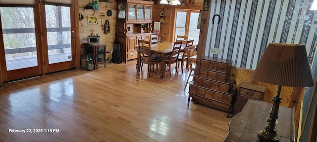 dining space featuring wainscoting, a healthy amount of sunlight, light wood-style flooring, and wallpapered walls