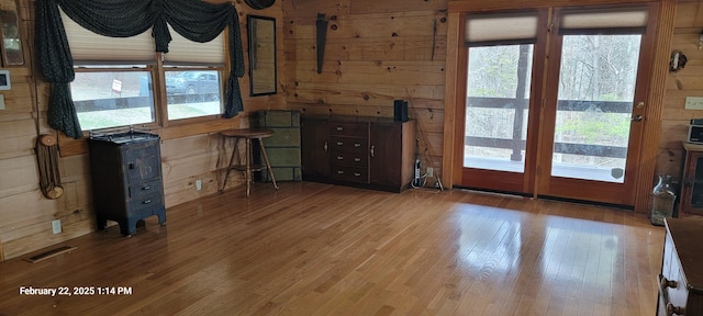 interior space featuring light wood-type flooring, visible vents, and wooden walls