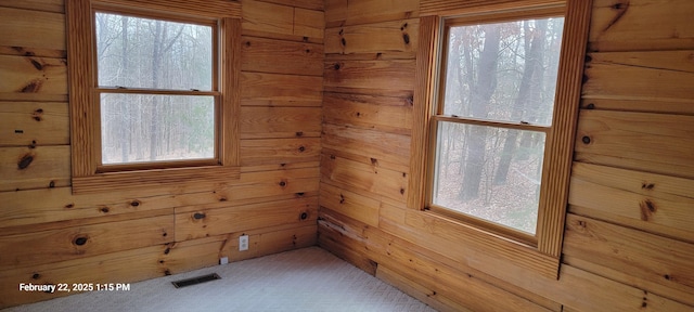 unfurnished room with wooden walls and visible vents