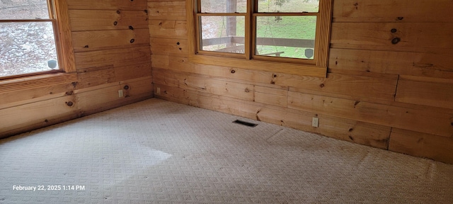 empty room featuring wood walls and visible vents