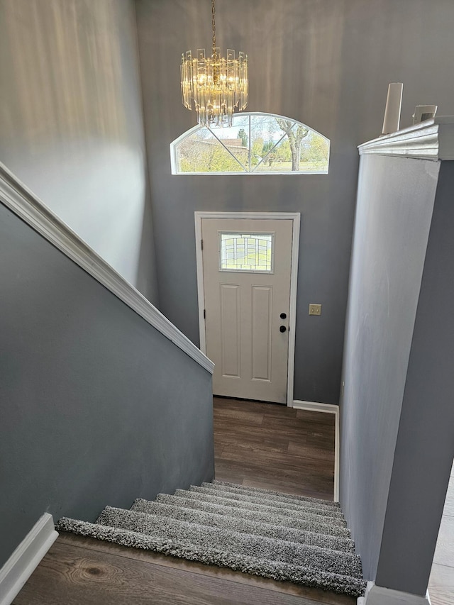 entrance foyer featuring wood-type flooring, a towering ceiling, and a notable chandelier