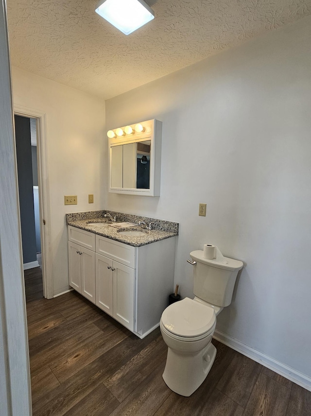 bathroom featuring hardwood / wood-style flooring, vanity, toilet, and a textured ceiling