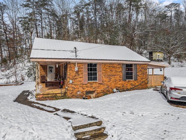 view of front of property with covered porch, brick siding, and metal roof