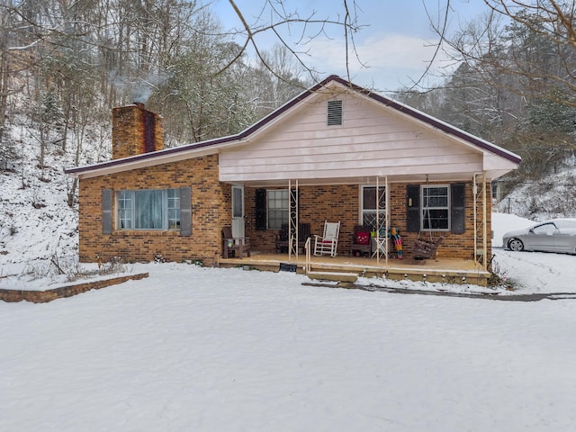 view of front of property with brick siding, a chimney, and a porch