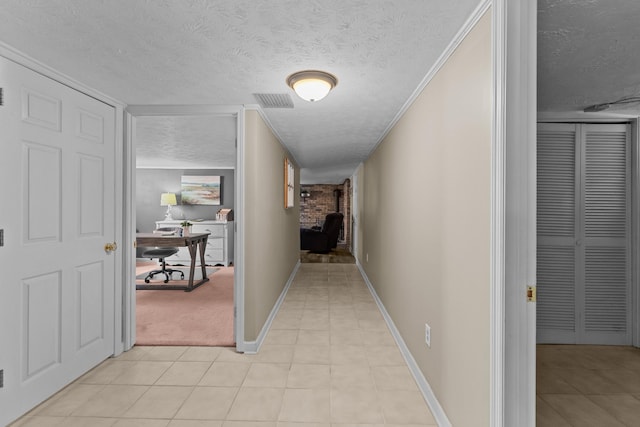 hallway featuring light tile patterned floors, baseboards, visible vents, and a textured ceiling