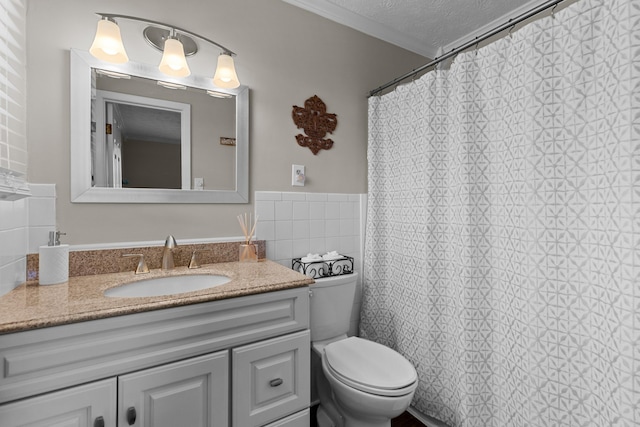 bathroom featuring a textured ceiling, toilet, vanity, tile walls, and crown molding