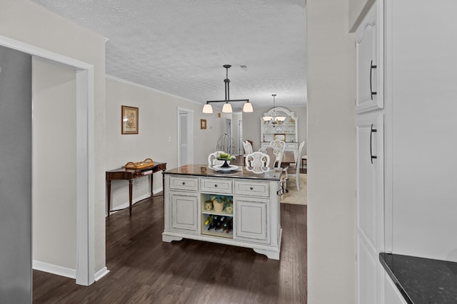 interior space featuring hanging light fixtures, an inviting chandelier, dark wood-type flooring, a textured ceiling, and baseboards