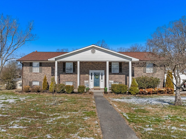 bi-level home with a front lawn and brick siding