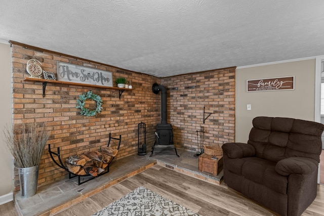 living room with a wood stove, a textured ceiling, and wood finished floors