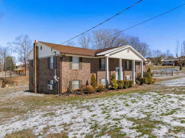 snow covered property with brick siding and a chimney