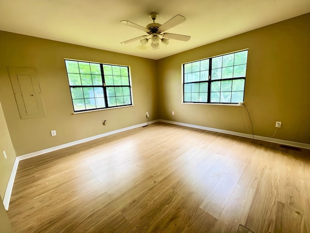 spare room with a ceiling fan, plenty of natural light, and wood finished floors