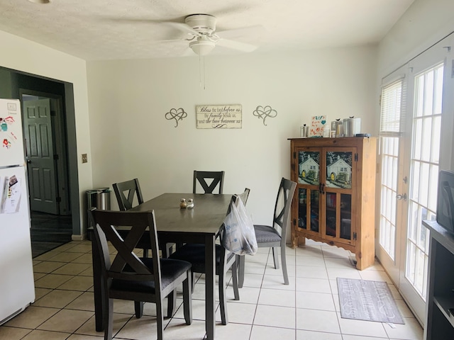 tiled dining space featuring ceiling fan and french doors