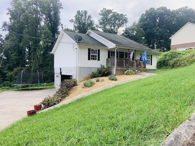 view of front of house with a porch, a trampoline, and a front lawn