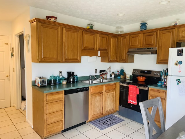 kitchen with a textured ceiling, sink, light tile patterned floors, and stainless steel appliances