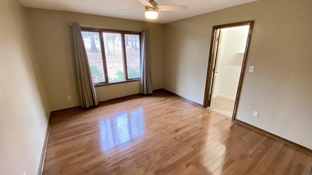 spare room featuring light wood-type flooring, a ceiling fan, and baseboards