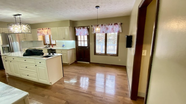 kitchen with light wood-style flooring, light countertops, a sink, and decorative light fixtures