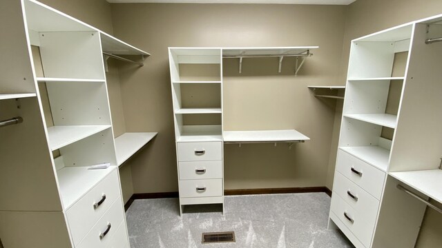 walk in closet featuring visible vents and light carpet