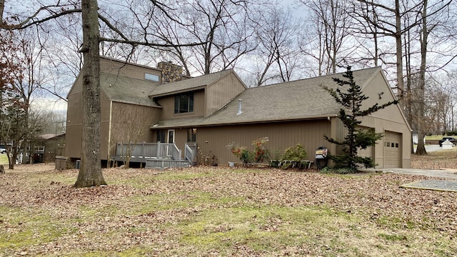 view of front of house featuring a garage, a shingled roof, a chimney, and a wooden deck