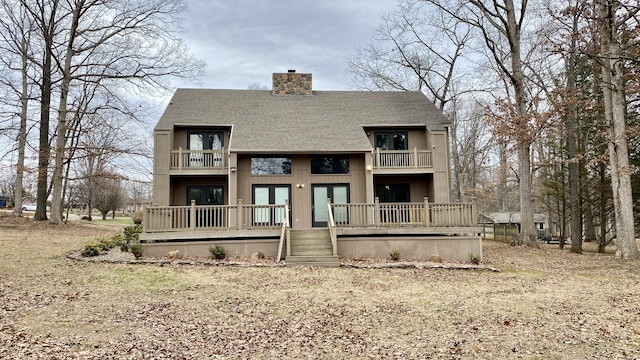 back of property with a balcony, roof with shingles, a chimney, and french doors