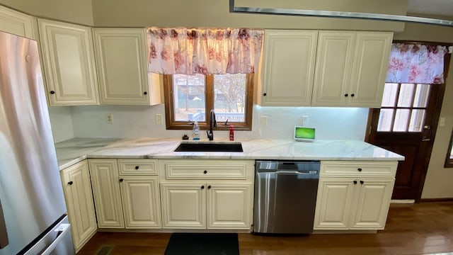 kitchen with stainless steel appliances, a sink, decorative backsplash, and light stone counters