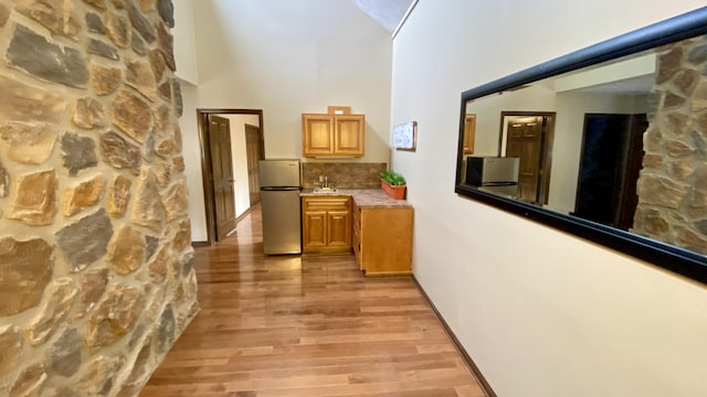 hallway featuring light wood-type flooring, a sink, and a towering ceiling