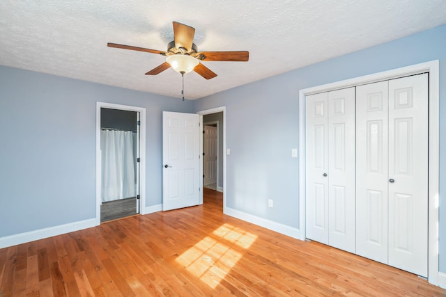 unfurnished bedroom featuring a textured ceiling, a closet, light hardwood / wood-style flooring, and ceiling fan