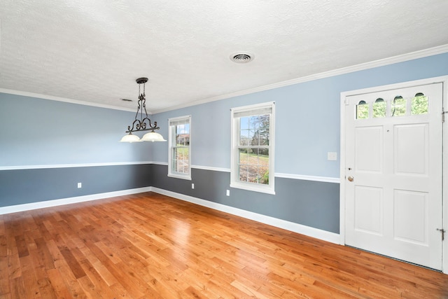 entryway with hardwood / wood-style floors, ornamental molding, and a textured ceiling