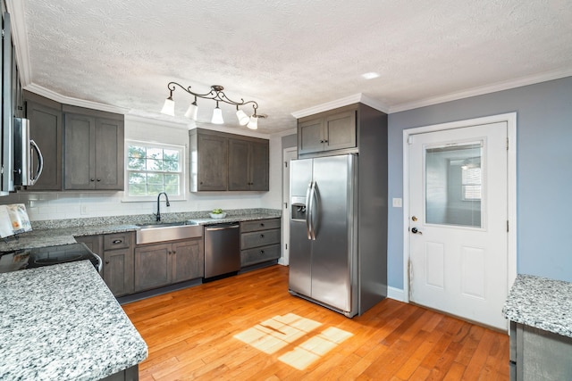 kitchen with light stone countertops, sink, stainless steel appliances, and light hardwood / wood-style floors