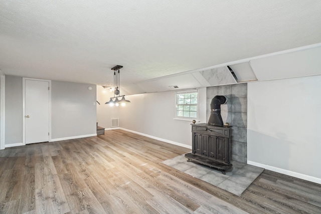 unfurnished living room with a wood stove, hardwood / wood-style floors, and a textured ceiling