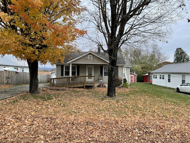 view of front of house with a front yard, a storage shed, and covered porch