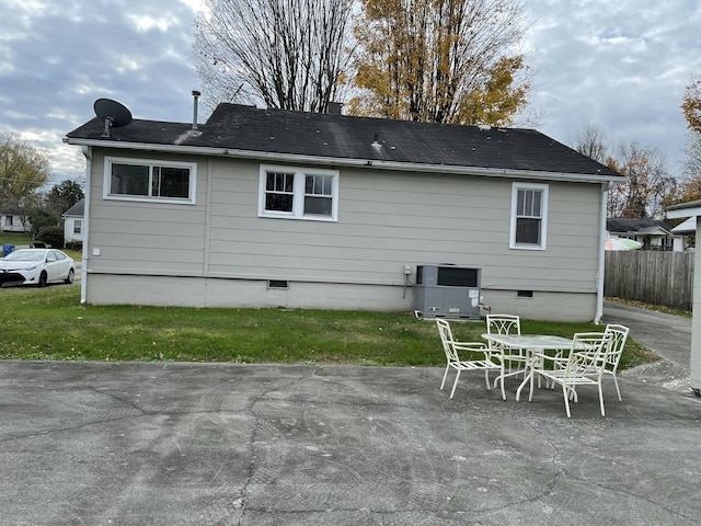 rear view of house featuring central air condition unit, a lawn, and a patio