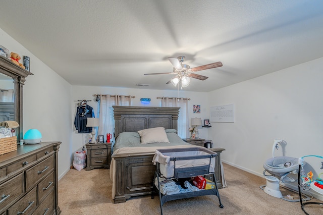 bedroom with a textured ceiling, light colored carpet, and ceiling fan