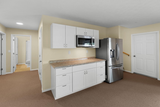 1114 Lake Ridge Dr, Dandridge, TN 37725 - kitchen featuring appliances with stainless steel finishes, dark colored carpet, light countertops, white cabinetry, and baseboards