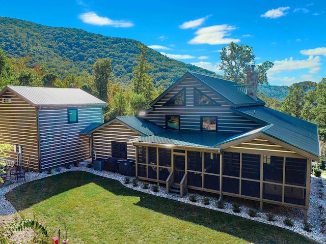 back of property with a lawn, a sunroom, and a mountain view