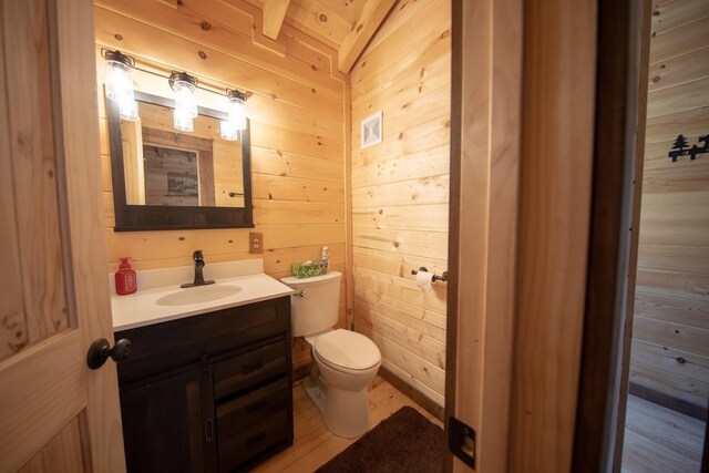 bathroom with vanity, lofted ceiling, wooden walls, toilet, and wood-type flooring