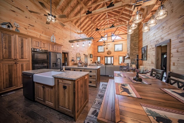 kitchen featuring black appliances, pendant lighting, a kitchen island with sink, and high vaulted ceiling