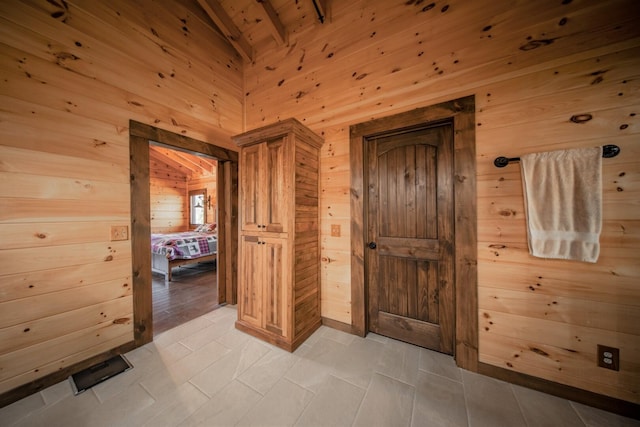 interior space featuring light tile patterned flooring, vaulted ceiling with beams, wooden ceiling, and wood walls