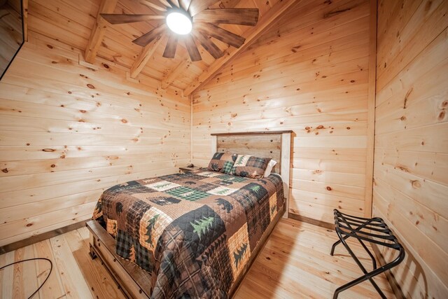 bedroom featuring vaulted ceiling with beams, wooden walls, ceiling fan, and light hardwood / wood-style floors